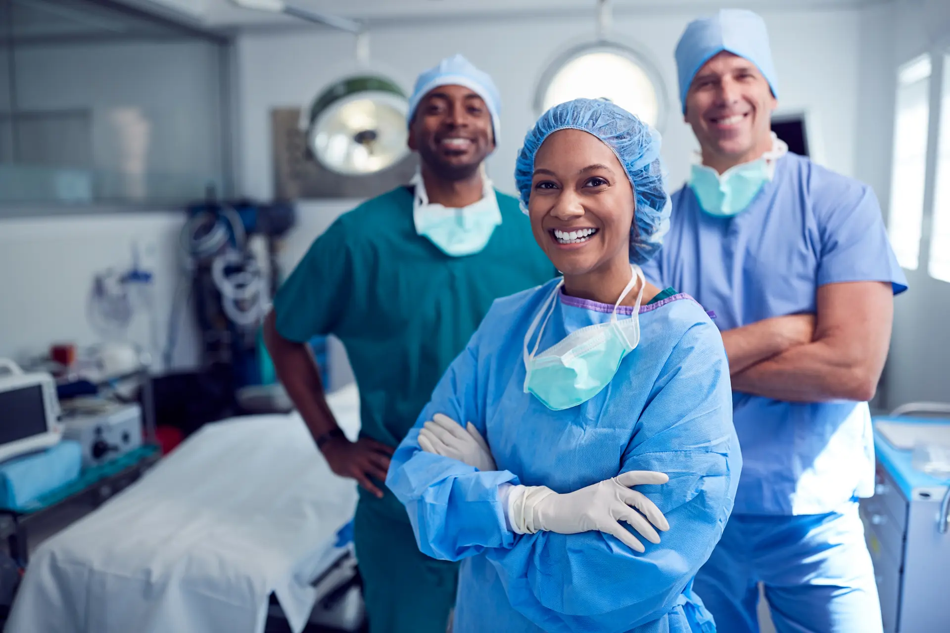 Smiling hospital surgical team in scrubs, masks and gloves