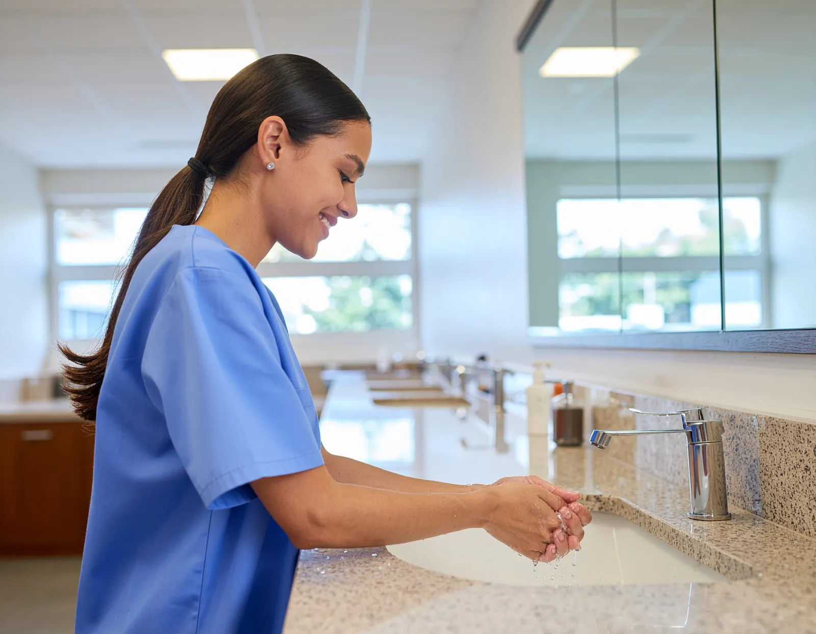 Healthcare worker washing hands at a clinic sink